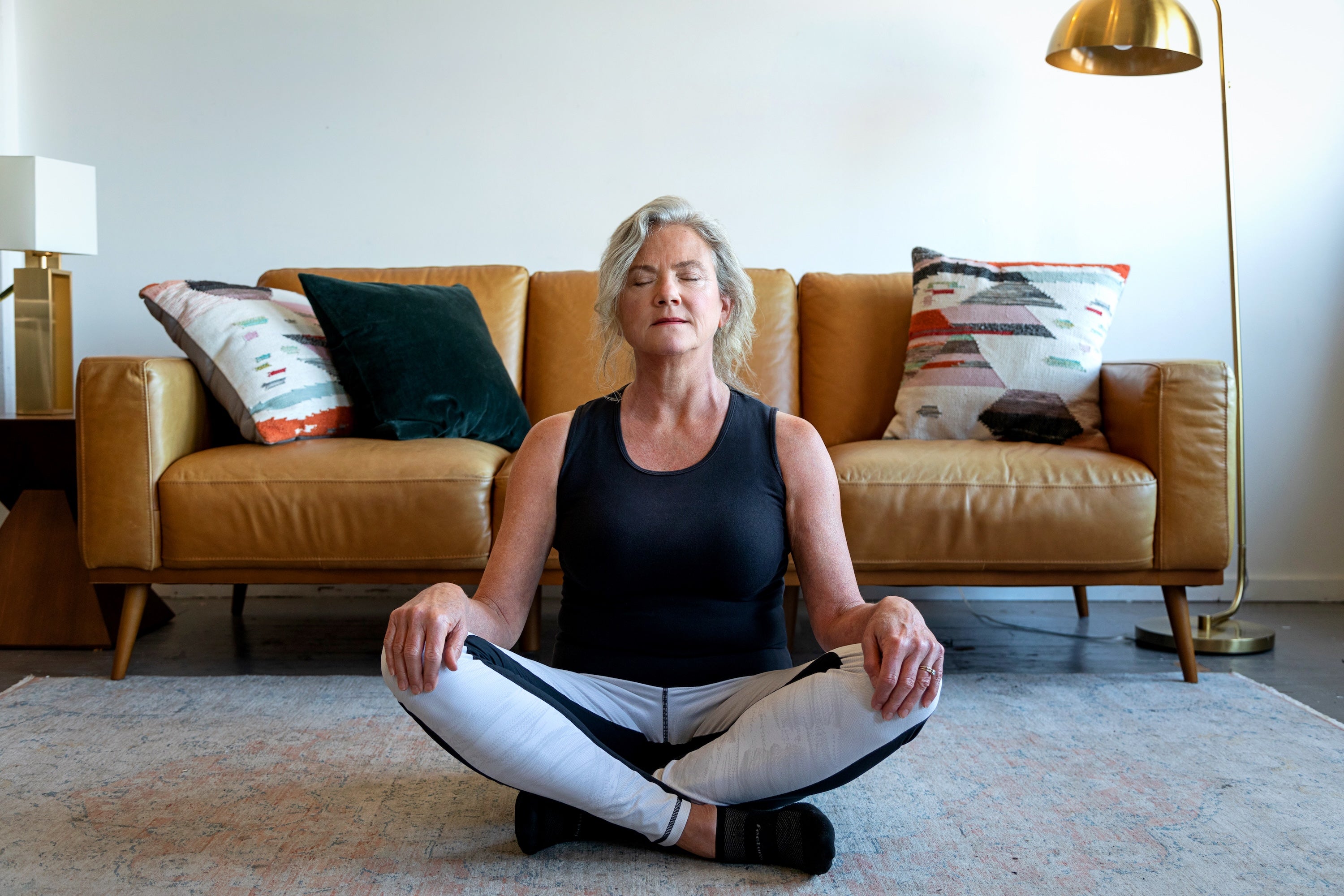 Older women in her 60's meditating in front of a coach.